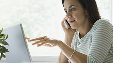 Woman talking on the phone and looking at her laptop screen